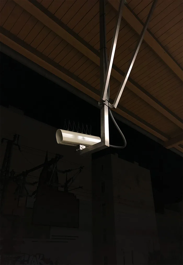 Camera suspended on metal rods under a dark wooden roof