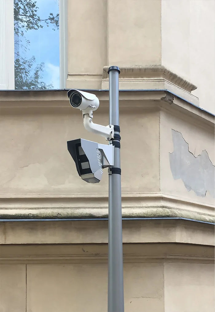 Two cameras on a pole in front of a weathered stone corner