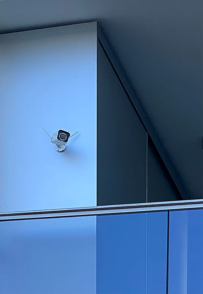 Small camera on a blue facade at the edge of a projecting corner