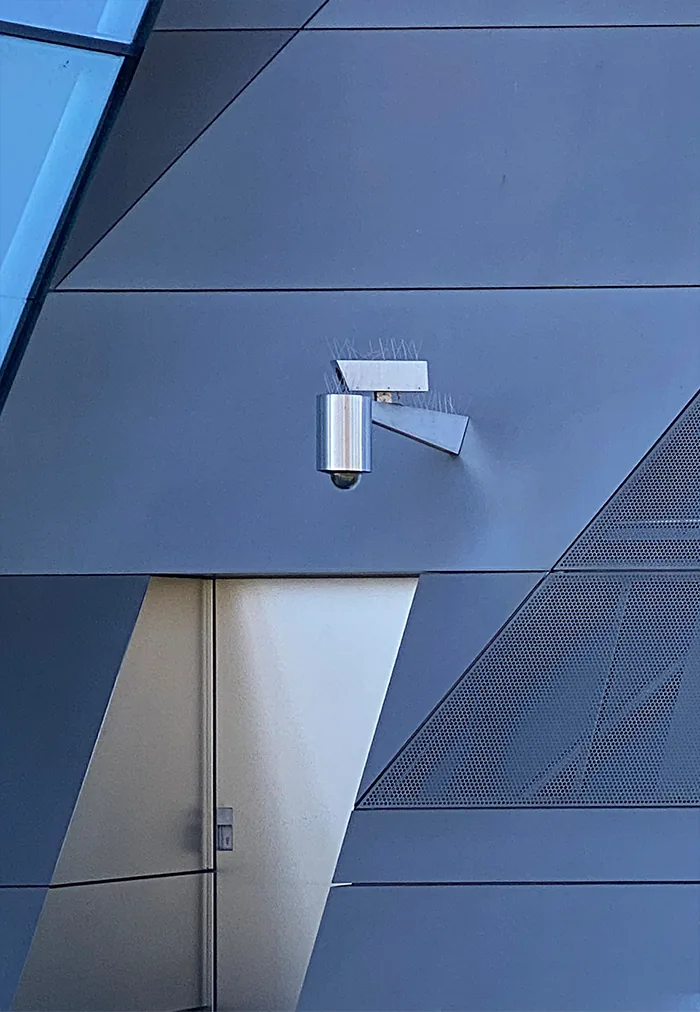 Silver camera on an angular blue-grey metal facade above a door